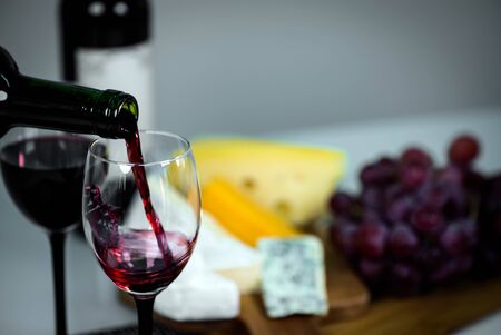 Cropped view sommelier pouring red wine from bottle into glassの写真素材