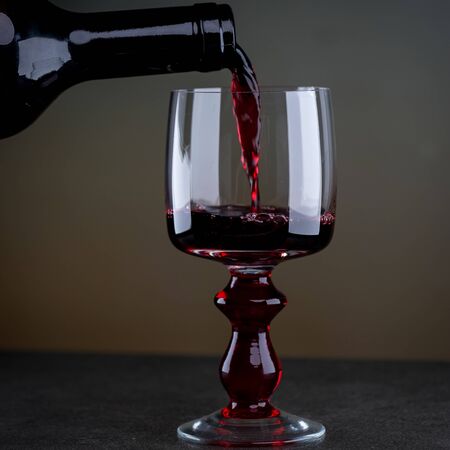 Cropped view sommelier pouring red wine from bottle into glassの写真素材