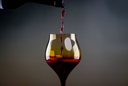 Red wine being poured into a glass close-upの写真素材