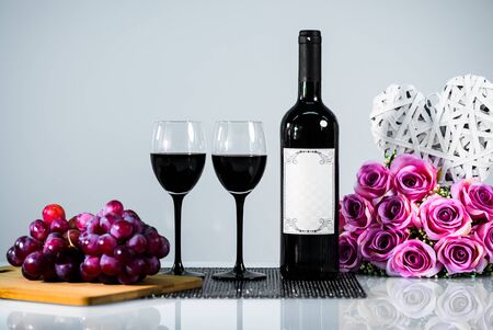 Red wine with grapes and flowers on whiteの写真素材