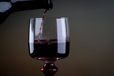 Red wine being poured into a glass close-upの写真素材