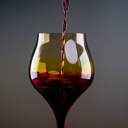 Red wine being poured into a glass close-upの写真素材