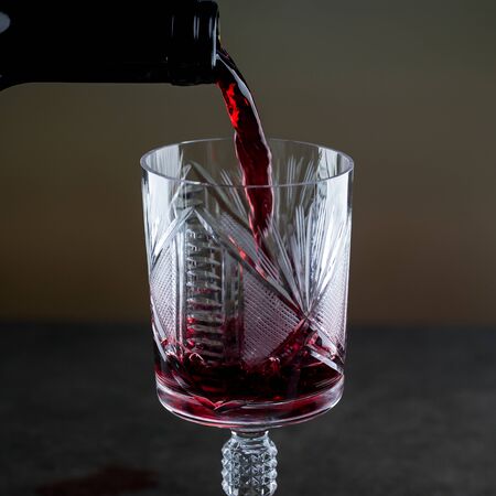 Red wine being poured into a glass close-upの写真素材