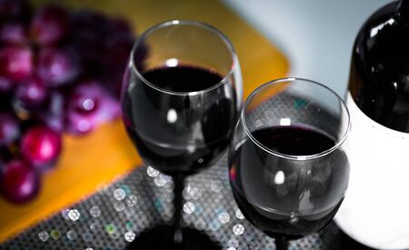 Pouring red wine from a bottle into a wineglass: wine tasting and celebrationの写真素材