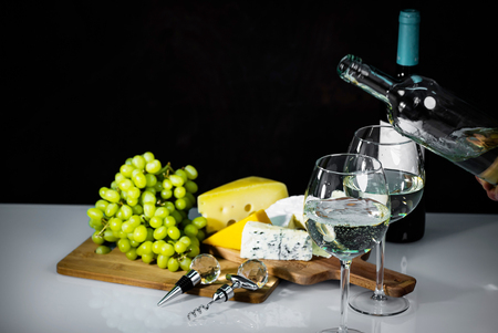 Pouring a white wine board with cheeses in the background