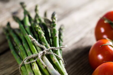 A bunch of fresh green asparagus on wooden boardの写真素材