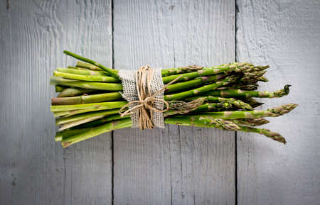 A bunch of fresh green asparagus on wooden boardの写真素材