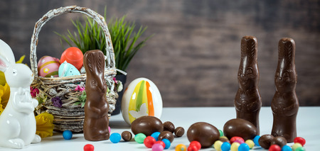 Delicious chocolate easter eggs, bunny and sweets on dark wood backgroundの写真素材