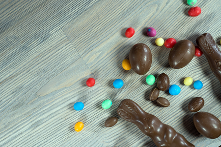 Delicious chocolate easter eggs, bunny and sweets on dark wood background