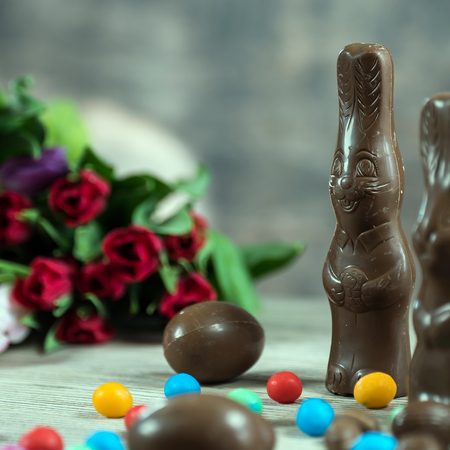 Delicious chocolate easter eggs, bunny and sweets on dark wood background