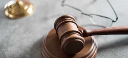 Law and Justice concept. Mallet of the judge, glasses, scales of justice. Gray stone background, reflections on the floor, place for typography. Courtroom theme.の写真素材