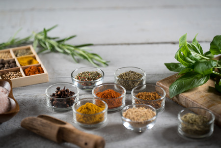 colorful fresh herbs and spices on a white wooden background