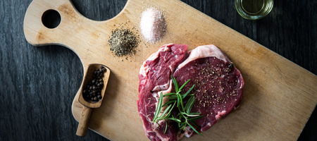 Raw beef steak on a wooden table.