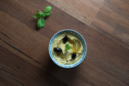 Hummus with olives and fresh herbs on a rustic tableの写真素材