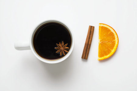 Top view of a coffee cup with cinnamon stick and orange slice on white background.の素材