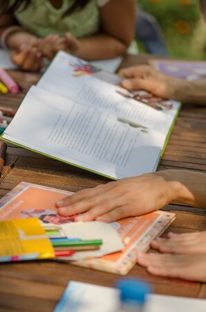 Teacher reading a story with some kids at a wooden tableの写真素材