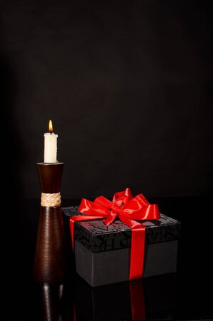 Gift box and candle against black backgroundの写真素材