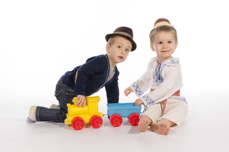 One child folk costume dressed  and other casual dressed playing with a train toyの写真素材