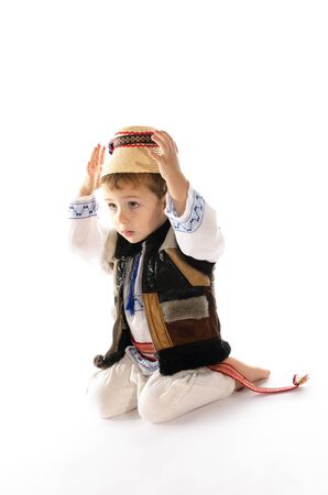 Portrait of beautiful child with traditional folk costume sitting on his kneesの写真素材