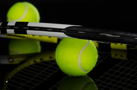 Tennis balls and racket against a black backgroundの写真素材