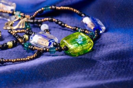Handmade jewellery necklace and earings presented on blue textileの写真素材