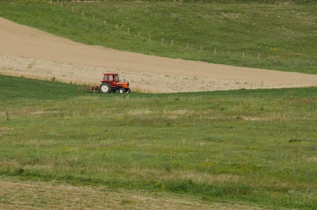 A man repairing a tractor on a wheat fieldの写真素材