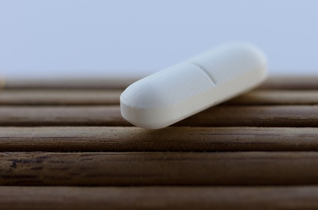 White pill on wooden surfaceの写真素材