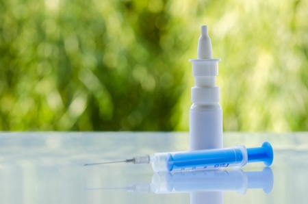 Bottle nose drop and syringe against green backgroundの写真素材