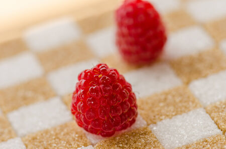 Raspberry on brown  and white sugar cubes arranged checker shape 