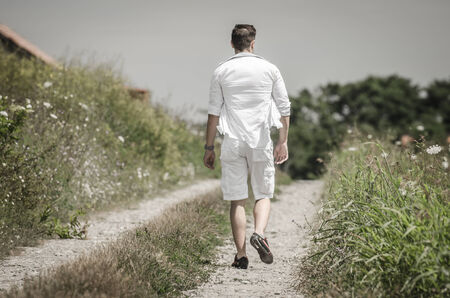 Happy young man with open arms in a field  under  the summer  sunの写真素材