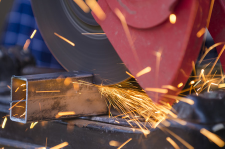 Tool cutting metal against dark background
