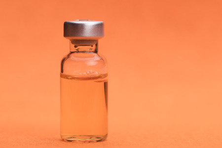 Ampoule ready to be used against  orange backgroundの写真素材