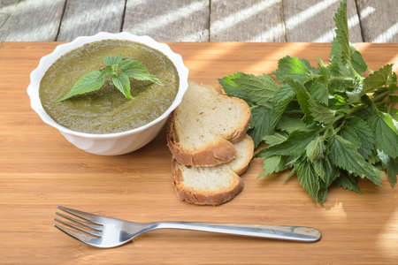 Nettle soup in a white bowl on a wooden surfaceの写真素材
