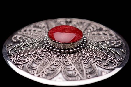 Red coral silver brooch against black backgroundの写真素材
