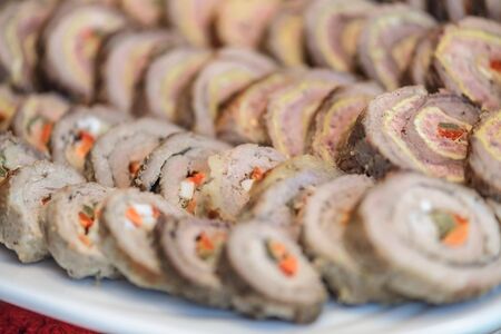 Appetizers with meat rolls, cheese and peppers on white plate close upの写真素材