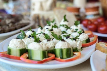 Appetizers with cucumbers and red peppers sliced and cheese on white plateの写真素材