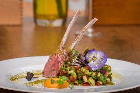 Lamb ribs with vegetables salad and edible flowers on white plateの写真素材