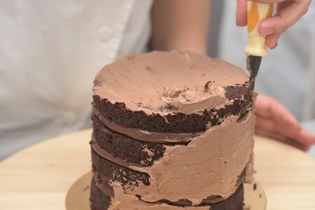 Showing how to wrap a dark chocolate cake with cocoa cream 