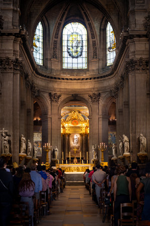 Paris, France 08 04 2023: A view of the nave in the Catholic cathedral of Saint-Sulpice in Paris, France, with people standing and listening to the priestのeditorial素材