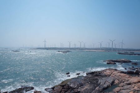 A wind power plant with dense coastlines in the distanceの写真素材