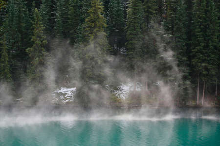 Alpine lake with mist rising in the early morningの写真素材