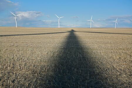 Shadow and wind turbines in stubble fieldの写真素材