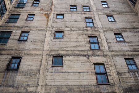 Grungy concrete wall with wood framed windows of an old city buildingの写真素材