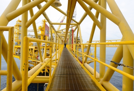 the worker is walking cross the pathway bridge of offshore oil rigの写真素材