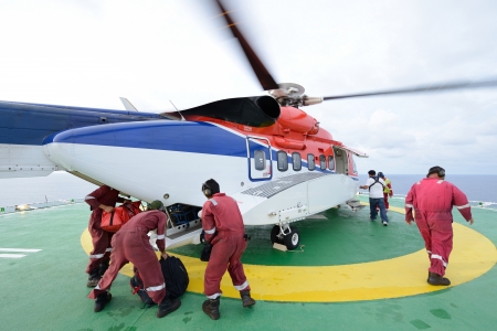 The helicopter landing officer are loading baggage and passenger to embark helicopter at oil rig...