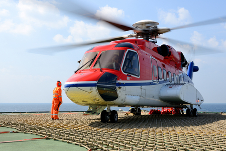 The helicopter landing officer take care loading baggage to helicopter at oil rig platformのeditorial素材