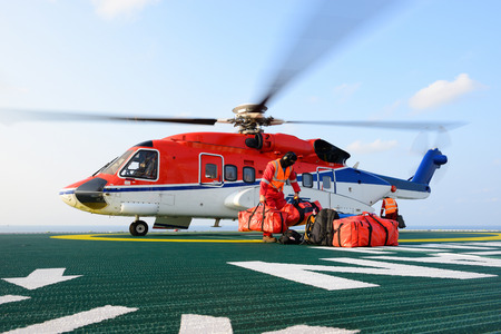 The helicopter landing officer loading baggage to helicopter at oil rig platformのeditorial素材