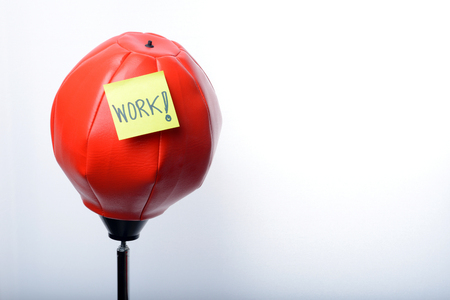 " WORK " handwritten on note Paper attached on red punching bag exercises on white backgroundの写真素材