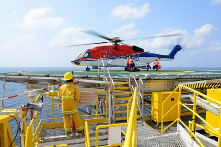 The landing officer are loading baggage of passenger to helicopter at oil rig platformの写真素材