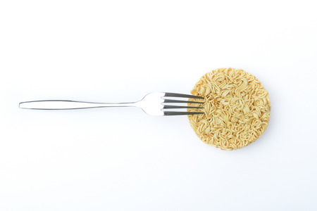 top view of raw instant noodles and stainless fork on white backgroundの写真素材